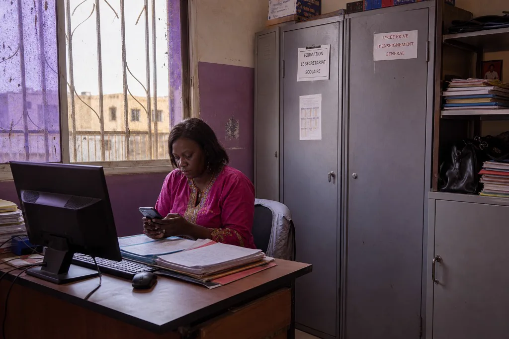 Secrétariat d'un lycée privé: dossiers papier, ordinateur et téléphone.